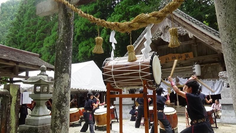 神社で中学生が複数の太鼓を演奏している様子