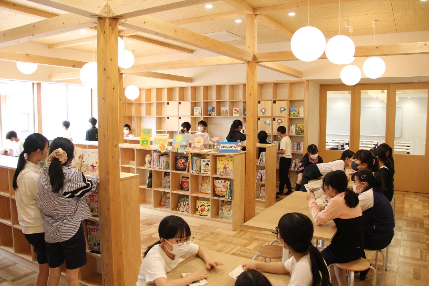 多くの児童が小学校の図書室で本を読んでいる写真