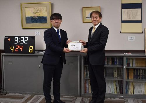 デンソーテン株式会社の職員と教育長が寄付金の受け渡しをいている様子