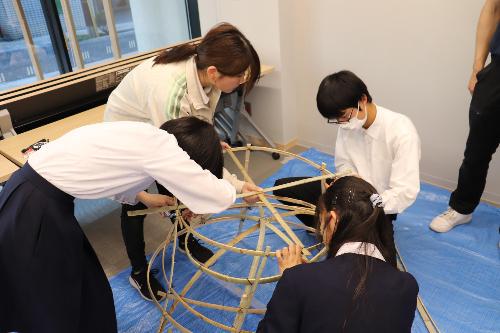 高校生がオブジェの竹組みを貼付けをしている様子