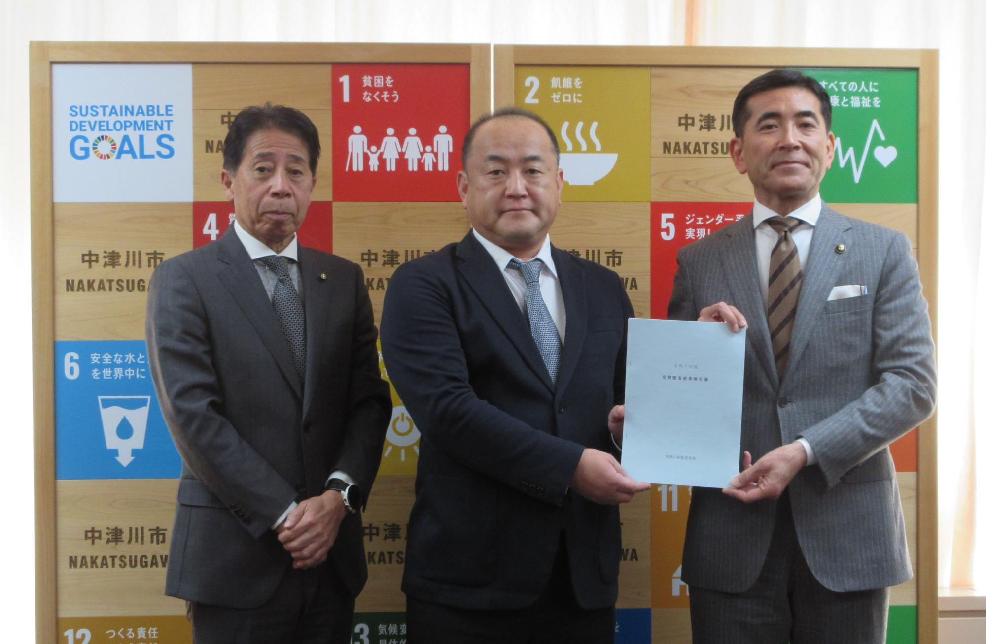 監査委員から市長へ報告書が手渡される様子