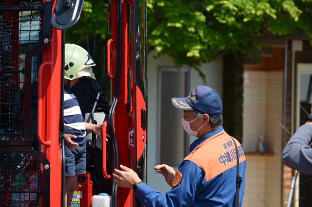 子どもが展示車両に乗って消防職員がサポートしています
