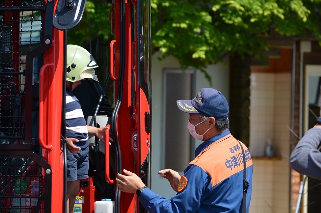 子どもが展示車両に乗って消防職員がサポートしています