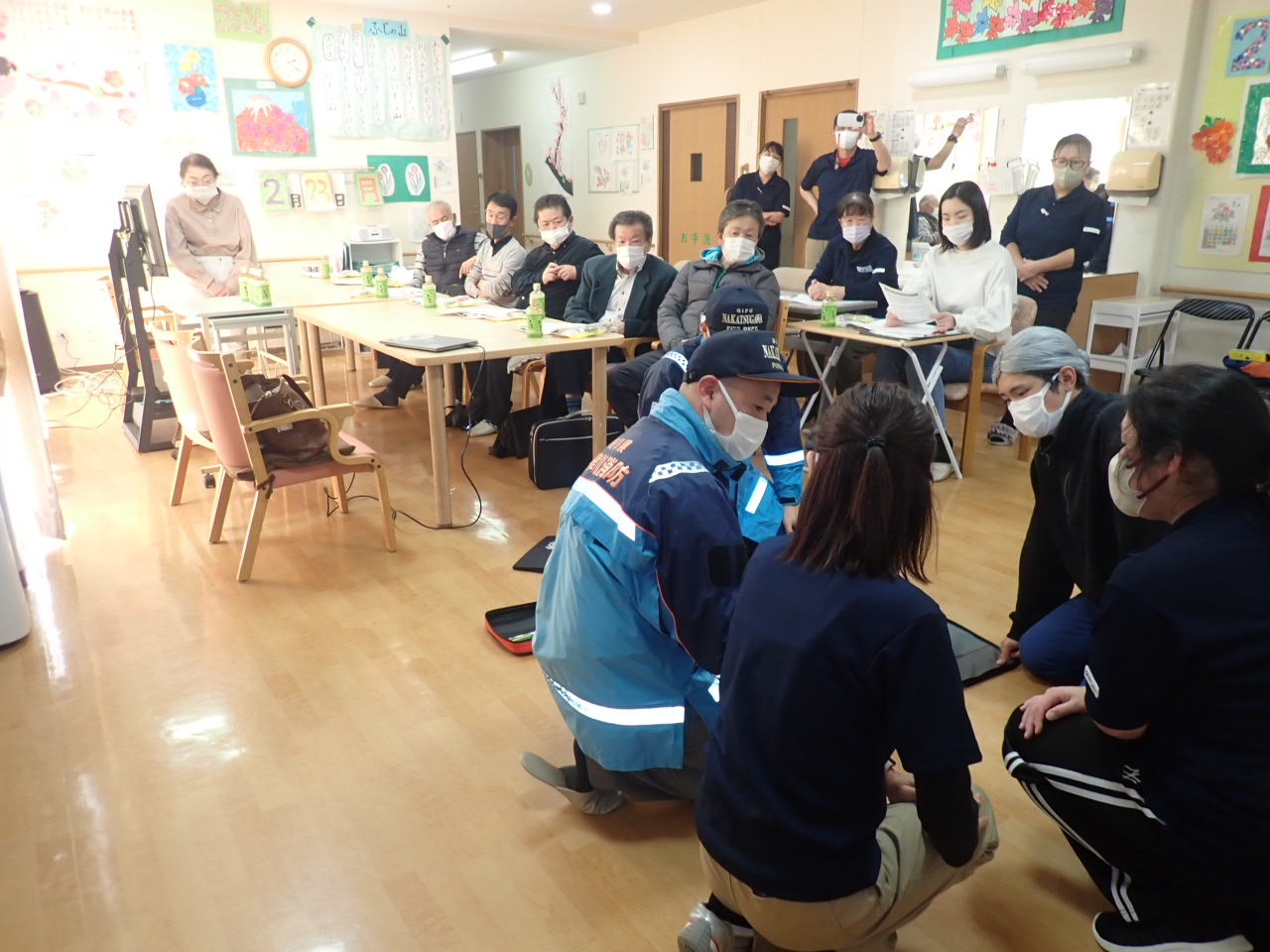 心臓マッサージの実践とそれを見学する参加者の様子