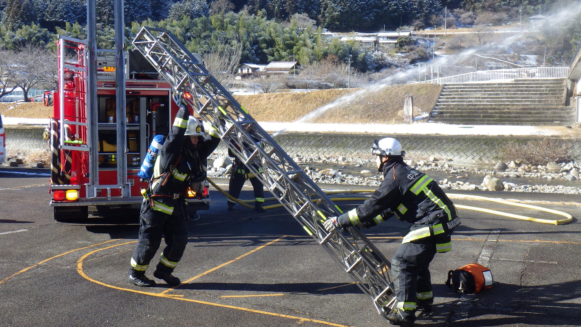 2階部分にはしごをかけようとする消防隊。消防車から放水する消防隊員。