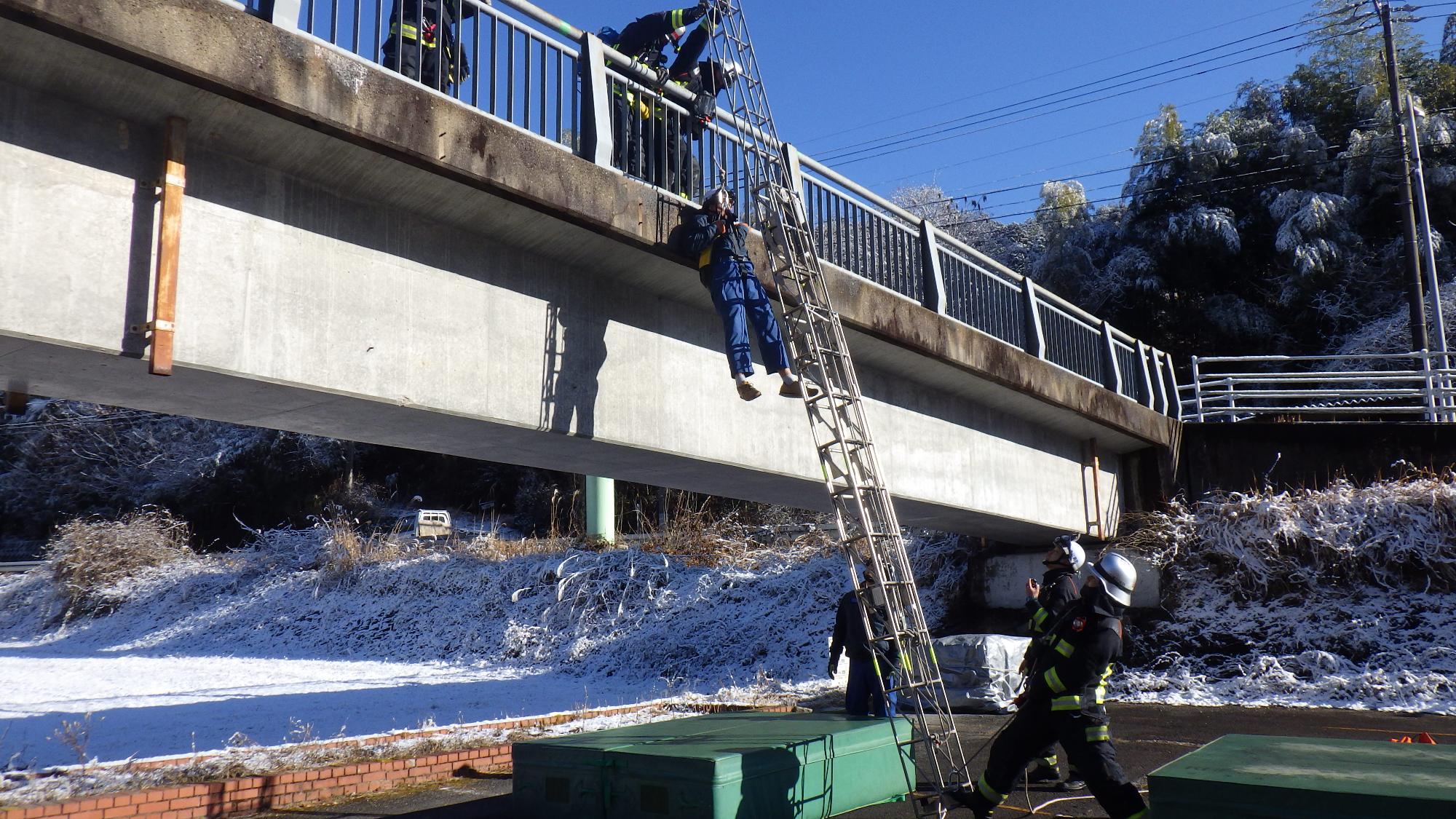 はしごを使用し、2階部分から逃げ遅れた人を救出する消防隊